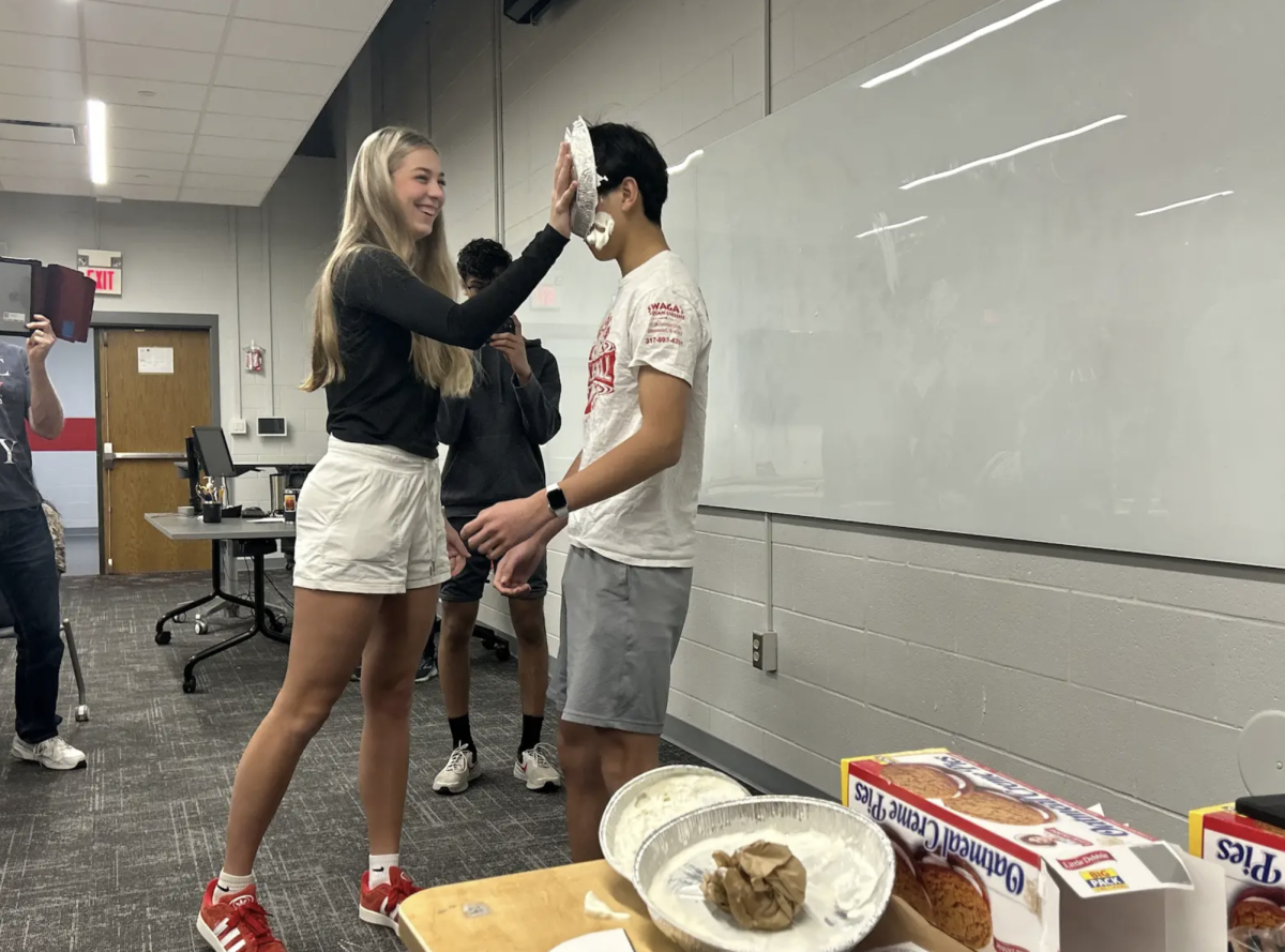 "To celebrate National Pi Day, Math National Honors Society enjoys pie related math activities. In this competition, members must solve complex math problems. The winners will get to pie the Society Officers in the face and enjoy oatmeal creme pies. Senior Reese Dunkle pies senior officer Alex Fan with a pie tin of whip creme. “Today's Math NHS meeting was more competitive than usual because instead of candy we got to pie an officer in the face”, says Dunkle.  This event made their usual math more fun and exciting. “I pied my friend Alex in the face which was funny and I’m glad I won the math competition”. 